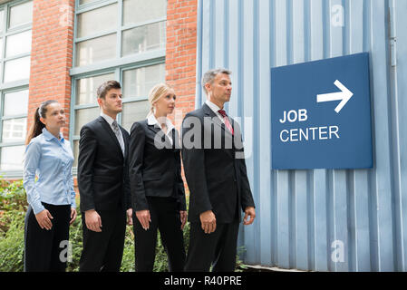 Businesspeople Standing Near The Job Center Signboard Stock Photo