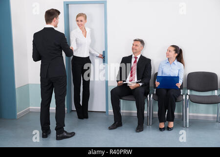 Businesswoman Shaking Hands With Man In Front Of People Stock Photo