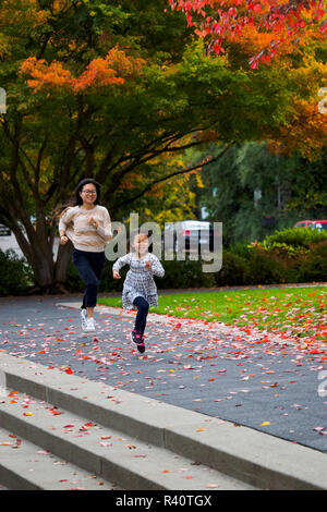 USA, Washington State, Bellevue. Young Asian girl and mother playing in the fall. Stock Photo
