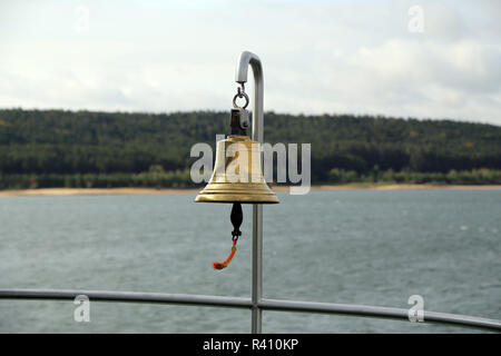 Copper bell on a yacht on the background of the coastline. Stock Photo