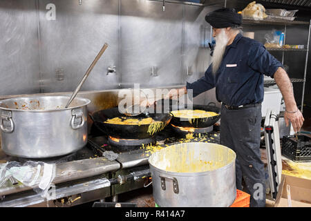 A Sikh man in a langar - communal kitchen - making bhature, Indian fried bread. At a temple in Queens, New York City. Stock Photo