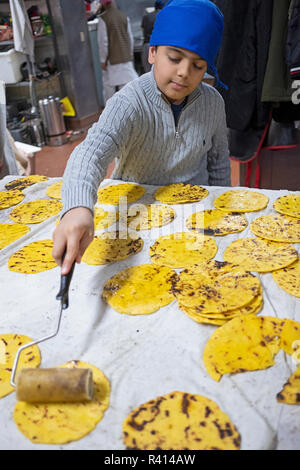 Fried indian bread roti in big pan. Hands making traditional indian ...