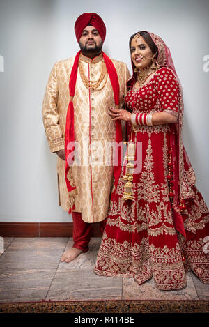 A Sikh bride and groom pose for a full length portrait in a temple after their wedding ceremony. I Queens, New York City. Stock Photo