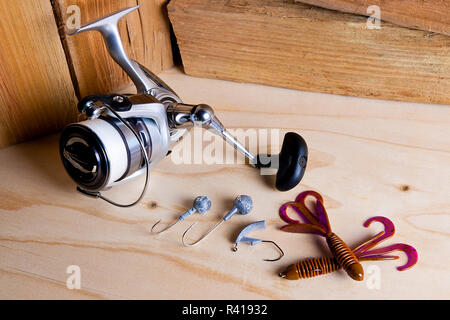 Fishing reel with silicone baits on wooden background. Stock Photo