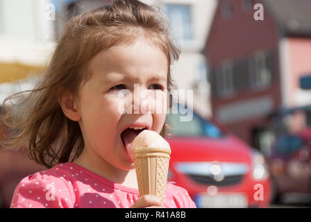 a little girl licking his ice cream cone in the city Stock Photo