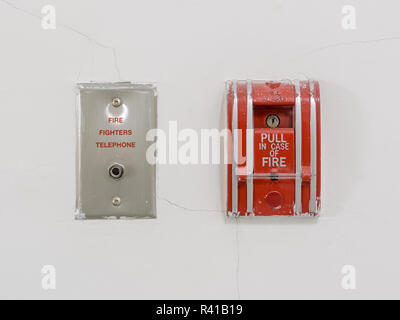 Red fire alarm pull station on wall Stock Photo