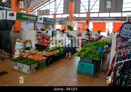 Woman customer examines and chooses fresh vegetables Satok market Kuching Malaysia Stock Photo