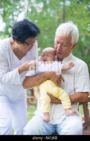 Asian crying baby comforted by grandparents at outdoor garden Stock Photo