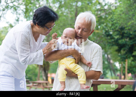 Asian crying baby comforted by grandparents at outdoor garden Stock Photo