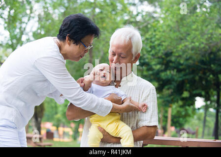 Asian crying baby comforted by grandparents at outdoor garden Stock Photo