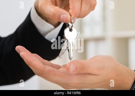 Person Hands Giving Key To Another Person Stock Photo