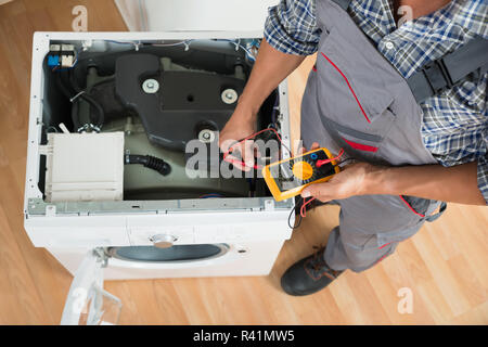 Technician Checking Washing Machine With Digital Multimeter Stock Photo