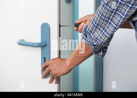 Technician Fixing Lock In Door With Screwdriver Stock Photo