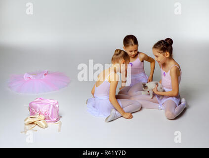 Three little ballet girls sitting in tutus and posing together Stock Photo