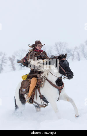 Cowgirl riding her horse wintertime Hideout Ranch, Shell, Wyoming. (MR ...