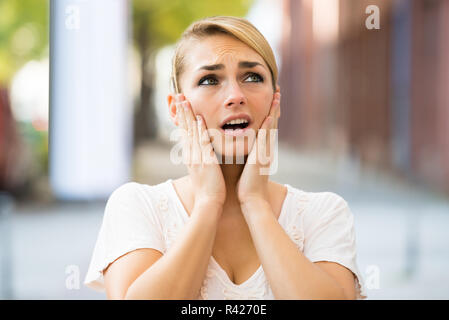 Woman With Hands On Face Looking Up Stock Photo