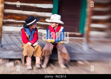 USA, Wyoming, Shell, Selective Focus of Young Cowboys Talking on porch of Old Cabin (MR) Stock Photo