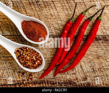 Cayenne peppers with ground cayenne and red pepper flake on a wood table background Stock Photo