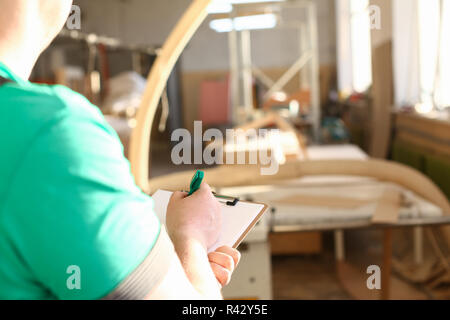 Arms of worker making notes on clipboard with green pen Stock Photo