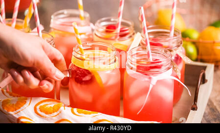 Raspberry lemonade garnished with fresh lemon and raspberries in drinking mason jars. Stock Photo