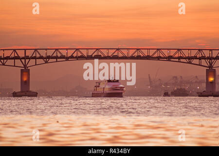 Traffic on bridge and sea crossing Mactan Bridge Cebu in misty dusk and sunset at golden hour Stock Photo