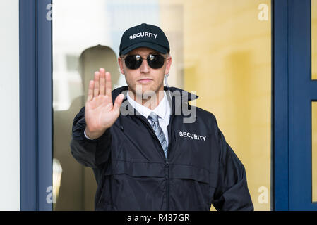 Confident security guard making stop gesture outside building Stock ...