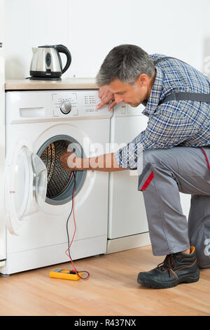 Repairman Checking Washing Machine With Digital Multimeter Stock Photo