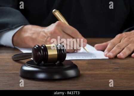 Judge Writing On Paper In Courtroom Stock Photo