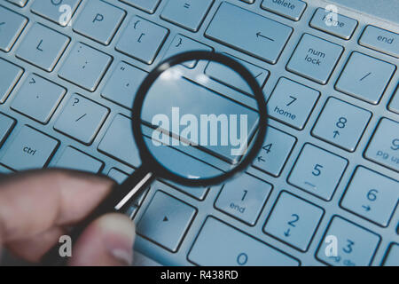 Blank button of laptop keyboard magnidied through the magnifying glass. Wordless key of a computer keypad viewed through the loupe. Write your text on computer keyboard. Concept of internet surfing. Stock Photo