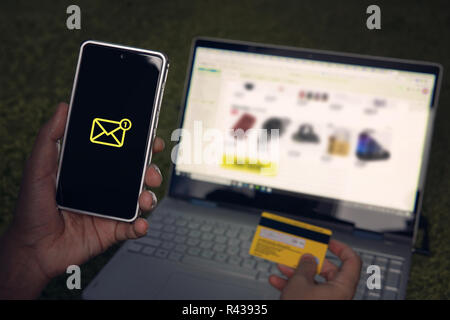 Man got one short message on smartphone being online on shooping website via laptop and holding credit card in hand. Concept of E-commerce using online banking service. Payment for internet purchase. Stock Photo