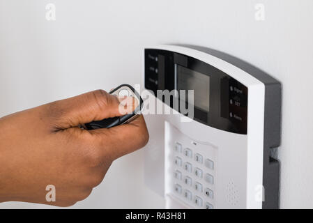 Person's Hand Using Remote To Operate Entrance Security System Stock Photo