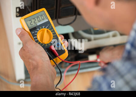 Repairman Checking Fridge With Digital Multimeter Stock Photo