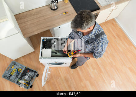 Technician Checking Washing Machine With Digital Multimeter Stock Photo