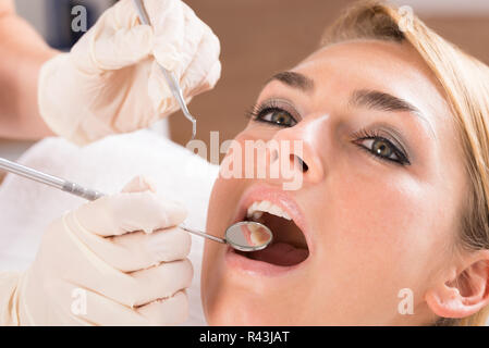 Dentist's Hands Examining Female Patient's Teeth Stock Photo