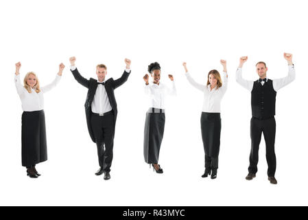 Happy Waiter And Waitresses Standing With Arms Raised Stock Photo