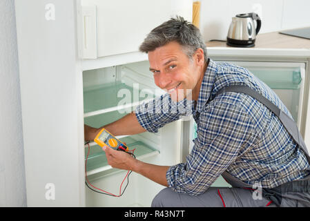 Technician Checking Fridge With Digital Multimeter Stock Photo