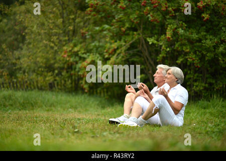 Nice mature couple meditating on green grass Stock Photo