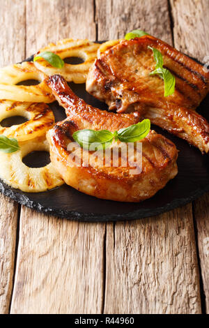 grilled bone-in pork chops on a black plate with lemon slice and ...