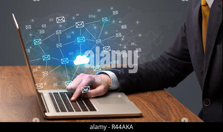 Businessman hand sending a bunch of messages on laptop with cloud Businessman hand sending a bunch of messages on laptop with cloud