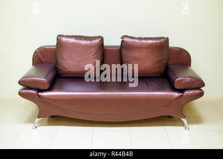 Leather sofa with pillows near the light wall. Stock Photo