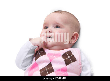 Smiling baby girl with finger in her mouth. Funny cute female newborn dressed in pink sweater isolated on white background. Stock Photo