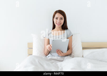 Woman sitting on bed and use of the digital tablet Stock Photo