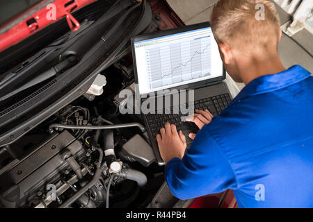 Mechanic Examining Car Engine With Help Of Laptop Stock Photo