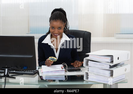 Businesswoman Holding Magnifying Glass Over Invoice Stock Photo