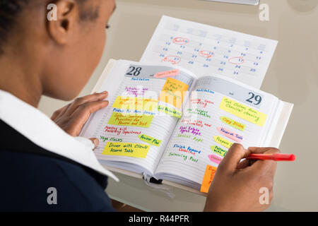 Businesswoman Writing Schedule In Diary Stock Photo