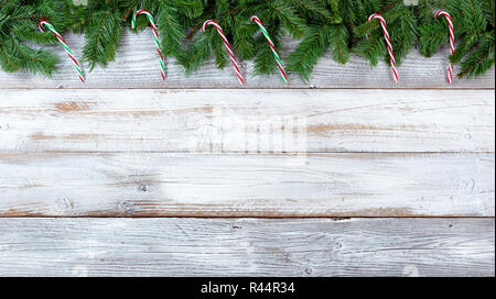 Top border of Christmas evergreen branches and candy canes on white vintage wood Stock Photo