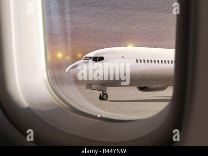 white aircraft in airport at non-flying weather, view  through window Stock Photo