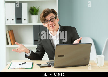 Technologies, emotions and business people concept - handsome man spreading his hands while he is working at computer, because he has some problems Stock Photo
