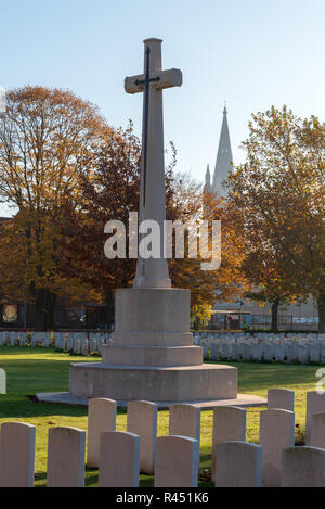 Cross of Sacrifice in Reservoir Cemetery with spire of St Martins Cathedral, Ypres Stock Photo