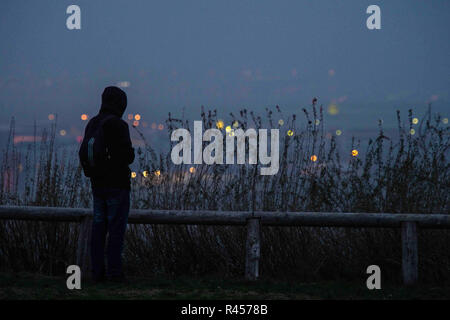 Berlin, Germany. 25th Nov, 2018. A man stands on the Dreidörferblick, a former garbage dump in Berlin-Rudow, and looks at an industrial area in Schönefeld during the 'blue hour' when the weather is hazy. Credit: Arne Bänsch/dpa/Alamy Live News Stock Photo
